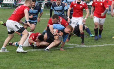 ODESSA, UKRAINE - 17 Nisan 2021: Rugby Kupası 7. Odessa Polytechnic Derby - mavi, CREDO - kırmızı. Erkeklerin ragbi maçının gergin anı. Dramatik ve zorlu erkek ragbi müsabakası. Erkekler ragbi sahasında savaşır