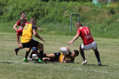Odessa, Ukrayna - 23 Haziran 2021: Odessa Milli Takımı CREDO (kırmızı) - OLYMP-Kharkiv (sarı) in rugby 7s. Top için erkek rugby oyuncularının sert agresif dövüşü. Stadyumun yeşil çimlerinde dinamik bir oyun