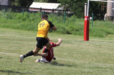Odessa, Ukrayna - 23 Haziran 2021: Odessa Milli Takımı CREDO (kırmızı) - OLYMP-Kharkiv (sarı) in rugby 7s. Top için erkek rugby oyuncularının sert agresif dövüşü. Stadyumun yeşil çimlerinde dinamik bir oyun