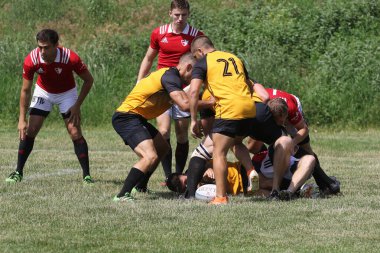 Odessa, Ukrayna - 23 Haziran 2021: Odessa Milli Takımı CREDO (kırmızı) - OLYMP-Kharkiv (sarı) in rugby 7s. Top için erkek rugby oyuncularının sert agresif dövüşü. Stadyumun yeşil çimlerinde dinamik bir oyun