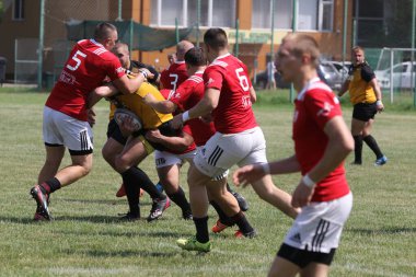 Odessa, Ukrayna - 23 Haziran 2021: Odessa Milli Takımı CREDO (kırmızı) - OLYMP-Kharkiv (sarı) in rugby 7s. Top için erkek rugby oyuncularının sert agresif dövüşü. Stadyumun yeşil çimlerinde dinamik bir oyun