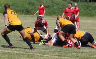 Odessa, Ukrayna - 23 Haziran 2021: Odessa Milli Takımı CREDO (kırmızı) - OLYMP-Kharkiv (sarı) in rugby 7s. Top için erkek rugby oyuncularının sert agresif dövüşü. Stadyumun yeşil çimlerinde dinamik bir oyun