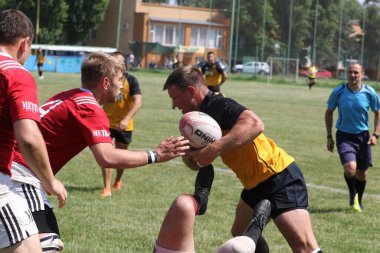 Odessa, Ukrayna - 23 Haziran 2021: Odessa Milli Takımı CREDO (kırmızı) - OLYMP-Kharkiv (sarı) in rugby 7s. Top için erkek rugby oyuncularının sert agresif dövüşü. Stadyumun yeşil çimlerinde dinamik bir oyun