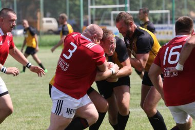 Odessa, Ukrayna - 23 Haziran 2021: Odessa Milli Takımı CREDO (kırmızı) - OLYMP-Kharkiv (sarı) in rugby 7s. Top için erkek rugby oyuncularının sert agresif dövüşü. Stadyumun yeşil çimlerinde dinamik bir oyun