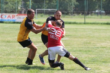 Odessa, Ukrayna - 23 Haziran 2021: Odessa Milli Takımı CREDO (kırmızı) - OLYMP-Kharkiv (sarı) in rugby 7s. Top için erkek rugby oyuncularının sert agresif dövüşü. Stadyumun yeşil çimlerinde dinamik bir oyun