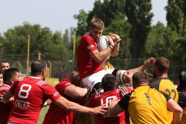 Odessa, Ukrayna - 23 Haziran 2021: Odessa Milli Takımı CREDO (kırmızı) - OLYMP-Kharkiv (sarı) in rugby 7s. Top için erkek rugby oyuncularının sert agresif dövüşü. Stadyumun yeşil çimlerinde dinamik bir oyun