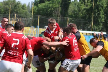 Odessa, Ukrayna - 23 Haziran 2021: Odessa Milli Takımı CREDO (kırmızı) - OLYMP-Kharkiv (sarı) in rugby 7s. Top için erkek rugby oyuncularının sert agresif dövüşü. Stadyumun yeşil çimlerinde dinamik bir oyun