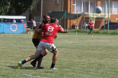 Odessa, Ukrayna - 23 Haziran 2021: Odessa Milli Takımı CREDO (kırmızı) - OLYMP-Kharkiv (sarı) in rugby 7s. Top için erkek rugby oyuncularının sert agresif dövüşü. Stadyumun yeşil çimlerinde dinamik bir oyun