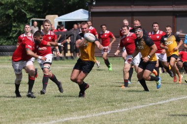 Odessa, Ukrayna - 23 Haziran 2021: Odessa Milli Takımı CREDO (kırmızı) - OLYMP-Kharkiv (sarı) in rugby 7s. Top için erkek rugby oyuncularının sert agresif dövüşü. Stadyumun yeşil çimlerinde dinamik bir oyun