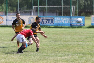 Odessa, Ukrayna - 23 Haziran 2021: Odessa Milli Takımı CREDO (kırmızı) - OLYMP-Kharkiv (sarı) in rugby 7s. Top için erkek rugby oyuncularının sert agresif dövüşü. Stadyumun yeşil çimlerinde dinamik bir oyun