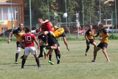 Odessa, Ukrayna - 23 Haziran 2021: Odessa Milli Takımı CREDO (kırmızı) - OLYMP-Kharkiv (sarı) in rugby 7s. Top için erkek rugby oyuncularının sert agresif dövüşü. Stadyumun yeşil çimlerinde dinamik bir oyun
