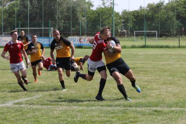 Odessa, Ukrayna - 23 Haziran 2021: Odessa Milli Takımı CREDO (kırmızı) - OLYMP-Kharkiv (sarı) in rugby 7s. Top için erkek rugby oyuncularının sert agresif dövüşü. Stadyumun yeşil çimlerinde dinamik bir oyun