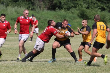 Odessa, Ukrayna - 23 Haziran 2021: Odessa Milli Takımı CREDO (kırmızı) - OLYMP-Kharkiv (sarı) in rugby 7s. Top için erkek rugby oyuncularının sert agresif dövüşü. Stadyumun yeşil çimlerinde dinamik bir oyun