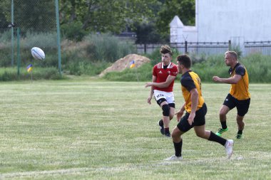 Odessa, Ukrayna - 23 Haziran 2021: Odessa Milli Takımı CREDO (kırmızı) - OLYMP-Kharkiv (sarı) in rugby 7s. Top için erkek rugby oyuncularının sert agresif dövüşü. Stadyumun yeşil çimlerinde dinamik bir oyun