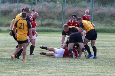 Odessa, Ukrayna - 23 Haziran 2021: Odessa Milli Takımı CREDO (kırmızı) - OLYMP-Kharkiv (sarı) in rugby 7s. Top için erkek rugby oyuncularının sert agresif dövüşü. Stadyumun yeşil çimlerinde dinamik bir oyun
