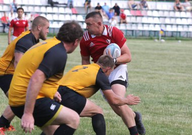 Odessa, Ukrayna - 23 Haziran 2021: Odessa Milli Takımı CREDO (kırmızı) - OLYMP-Kharkiv (sarı) in rugby 7s. Top için erkek rugby oyuncularının sert agresif dövüşü. Stadyumun yeşil çimlerinde dinamik bir oyun