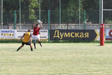 Odessa, Ukrayna - 23 Haziran 2021: Odessa Milli Takımı CREDO (kırmızı) - OLYMP-Kharkiv (sarı) in rugby 7s. Top için erkek rugby oyuncularının sert agresif dövüşü. Stadyumun yeşil çimlerinde dinamik bir oyun
