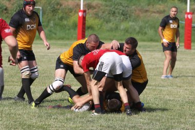 Odessa, Ukrayna - 23 Haziran 2021: Odessa Milli Takımı CREDO (kırmızı) - OLYMP-Kharkiv (sarı) in rugby 7s. Top için erkek rugby oyuncularının sert agresif dövüşü. Stadyumun yeşil çimlerinde dinamik bir oyun