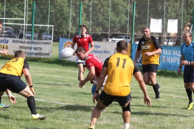 Odessa, Ukrayna - 23 Haziran 2021: Odessa Milli Takımı CREDO (kırmızı) - OLYMP-Kharkiv (sarı) in rugby 7s. Top için erkek rugby oyuncularının sert agresif dövüşü. Stadyumun yeşil çimlerinde dinamik bir oyun