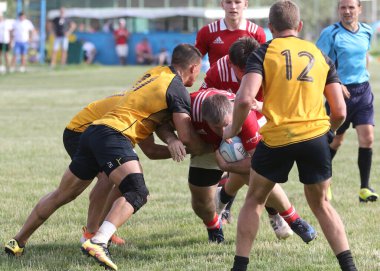 Odessa, Ukrayna - 23 Haziran 2021: Odessa Milli Takımı CREDO (kırmızı) - OLYMP-Kharkiv (sarı) in rugby 7s. Top için erkek rugby oyuncularının sert agresif dövüşü. Stadyumun yeşil çimlerinde dinamik bir oyun