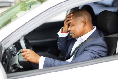 Stresli siyahi işadamı arabada oturuyor, direksiyon başında oturuyor ve kafaya dokunuyor, düşünceli ve yorgun ifade, iş gezisi sırasında stres ve seyahat yorgunluğu kavramı