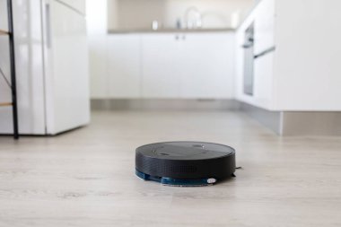 Robot vacuum cleaner working on kitchen floor. Smart cleaning technology for modern household automation and daily floor maintenance with efficiency and ease