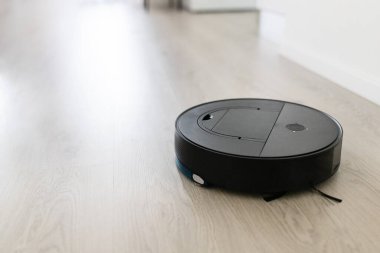Autonomous robot vacuum cleaning bright modern floor. Smart home appliance for daily cleaning automation and efficient maintenance of domestic environments