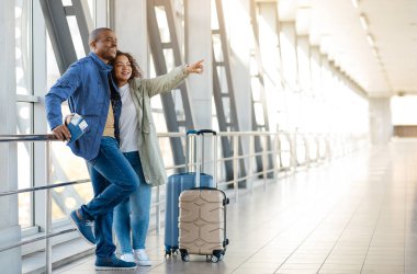 Havalimanında bavullarıyla bekleyen neşeli Afrikalı çift ve mutlu Afrikalı eşler terminalde bekliyor ve ayrılmadan önce birlikte vakit geçiriyorlar.. 