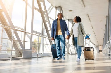 Havaalanı Terminali 'nde yürüyen, uçuştan önce dinlenen mutlu Afrikalı Amerikalı çift. Yüksek kalite fotoğraf