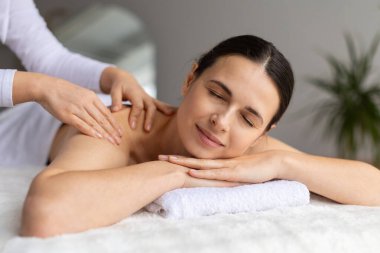 Genç bir bayan modern spa merkezinde tam sırt masajı yaptırıyor. Terapistlerin elleri onun sırtında sorunsuzca süzülüyor, rahatlığı, sağlık bakımını ve huzur verici, rahatlatıcı bir güzellik deneyimini arttırıyor.