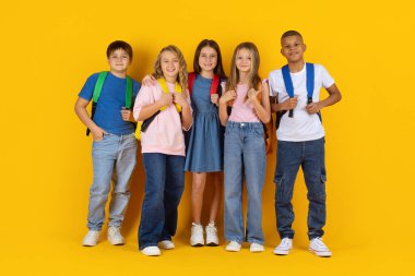 Neşeli bir grup genç öğrenci parlak bir stüdyo arka planında birlikte duruyorlar. Sırt çantalı gülümseyen çocuklar enerji ve pozitiflikle dolu bir okul hayatı için poz veriyorlar.