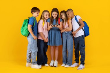 Bir grup okul çocuğu ellerinde akıllı telefonuyla parlak bir stüdyo geçmişine sahip bir kızın etrafında toplandı. Arkadaş canlısı çocuklar modern dijital anı birlikte paylaşıyorlar.