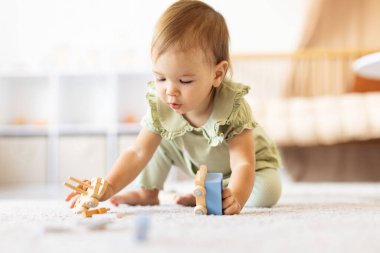 Diz çöküp tahta oyuncakları merakla keşfeden küçük bir kız. Işıl ışıl ev içleri erken öğrenmeyi, iyi bir motor gelişimini ve sıcak, huzurlu bir çocukluk anını ön plana çıkarıyor.