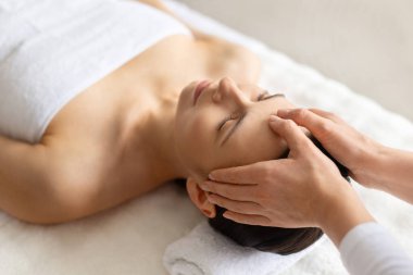 Beyaz kadın lüks kaplıcalarda yüz masajı yaptırıyor, gözleri kapalı, cilt bakımına odaklanan nazik masaj, sağlık rutini, güzellik bakımı ve tam rahatlama.