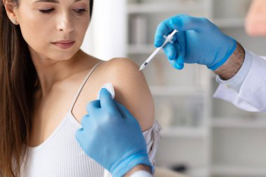 Doktor mavi eldiven takıyor. Kadın hastaya aşı yapıyor. Aşılama ve önleme konsepti.