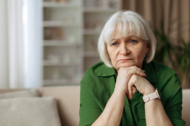 Yaşlı beyaz kadın düşünceli görünüyor, elleri çene altında dinlenirken, yaşlı kadın derin yansıması, sessiz emeklilik yaşam tarzı ve duygusal denge kavramı