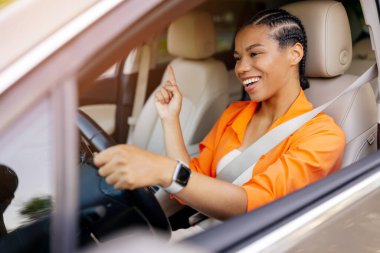 Mutlu genç siyahi kadın araba sürüyor ve heyecanla yukarı doğru işaret ediyor güvenli ve keyifli şehir seyahati sırasında pozitif ruh hali ve güven gösteriyor.