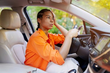 Araba kullanırken alnını mendille silen genç siyahi kadın yorgun ve stresli görünüyor. Afrika kökenli Amerikalı bir sürücü işe gidip gelirken rahatsızlandı.