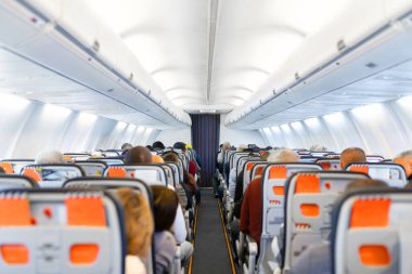 Uçuş sırasında oturan yolcularla birlikte uçak kabininin içinde. Uçak seyahati ve ulaşım geçmişi ticari uçak koridoru ve koltuklarını gösteriyor.