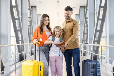 Aileler ve kızları havaalanı terminalinde pasaport kontrolü, aile tatili ve yurt dışına tatil seyahatinden önce seyahat belgelerini birlikte gözden geçiriyorlar.