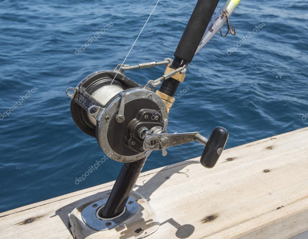 Closeup of fishing rod reel on side of boat Stock Photo by