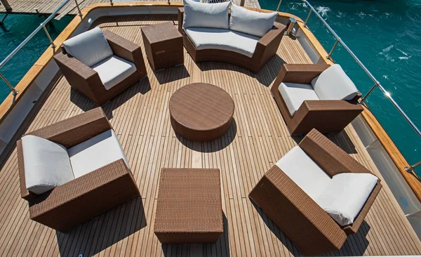 Rear teak deck of a large luxury motor yacht with chairs sofa and table
