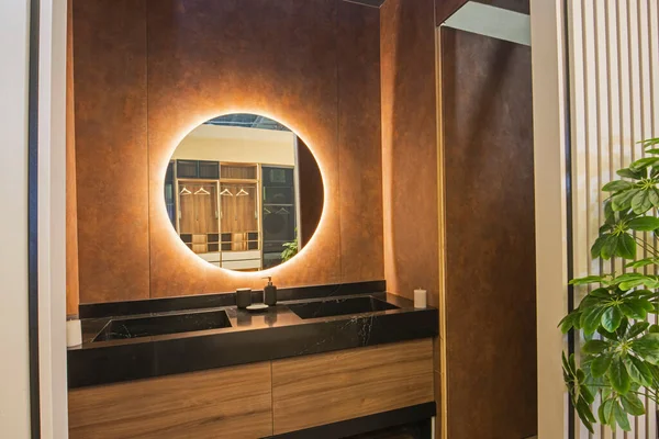 Interior design of a luxury show home bathroom with twin sinks and round mirror