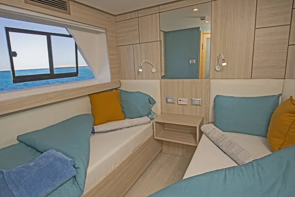 Interior of cabin bedroom on luxury sailing yacht with twin beds and sea view