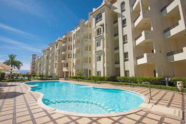 Lüks bir tropikal otel tesisinde büyük bir yüzme havuzu ve tabureleri.