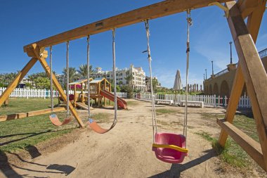 Tropikal tatil beldesindeki kaydırağıyla çocuk parkında çerçeve yapısını sallar