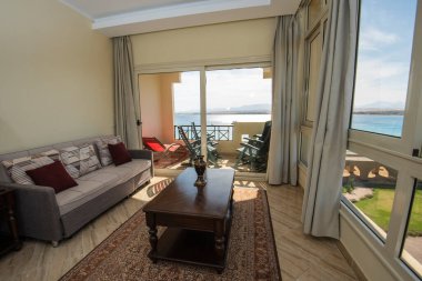 Lüks apartmandaki oturma odası salonu balkon ve deniz manzaralı iç dekorasyon dekorasyonunu gösteriyor.