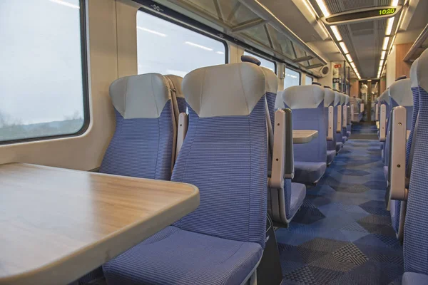 座席とテーブルの行を持つ無人通勤電車の中のインテリアの眺め — ストック写真