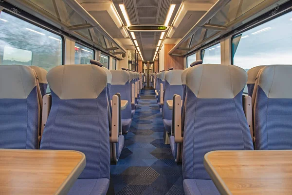 座席とテーブルの行を持つ無人通勤電車の中のインテリアの眺め — ストック写真