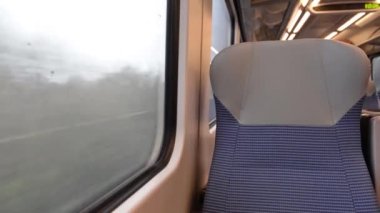 Terkedilmiş boş bir banliyö vagonundaki iç mekan manzarası. Sıralar halinde koltuklar ve masalar kırsal alanda seyahat ediyor.